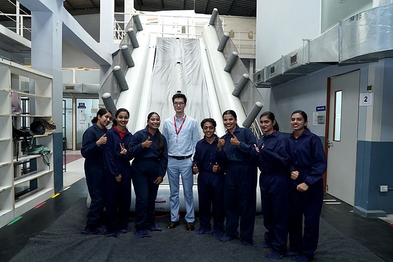 Trainees in coveralls in front of an aircraft evacuation slide