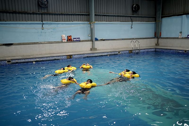 Trainees in life jackets practising a ditching drill in the pool